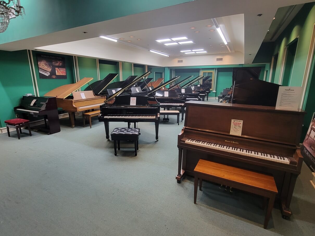 This is an overview picture of the green room, with many variations of grand piano, just past the foyer room inside Piano Man Superstore.